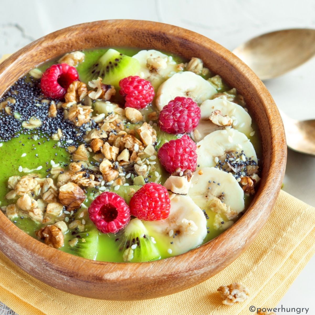 green smoothie bowl topped with fruits nuts and seeds