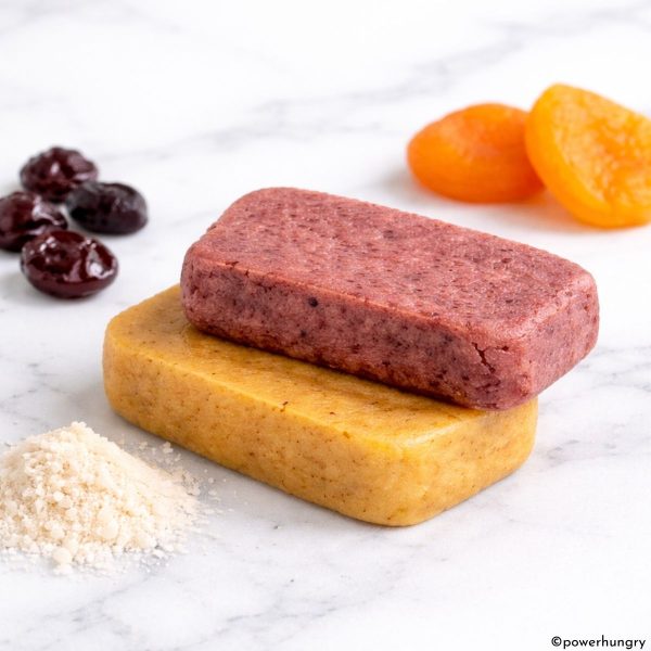 fruit protein bars, stacked, with dried fruits and coconut flour alongside