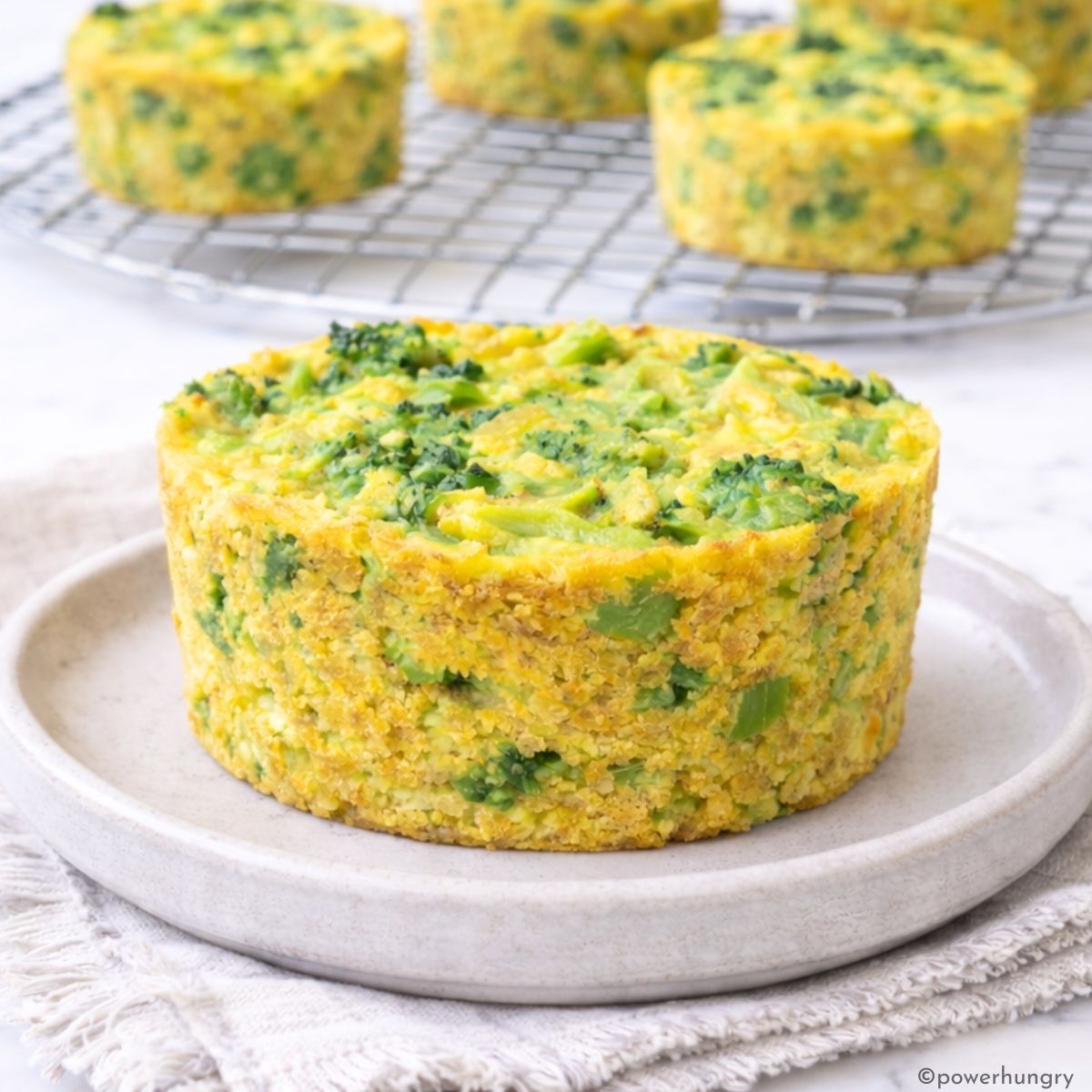 vegan broccoli cheese rice casserole muffin on a small plate, with more in the background