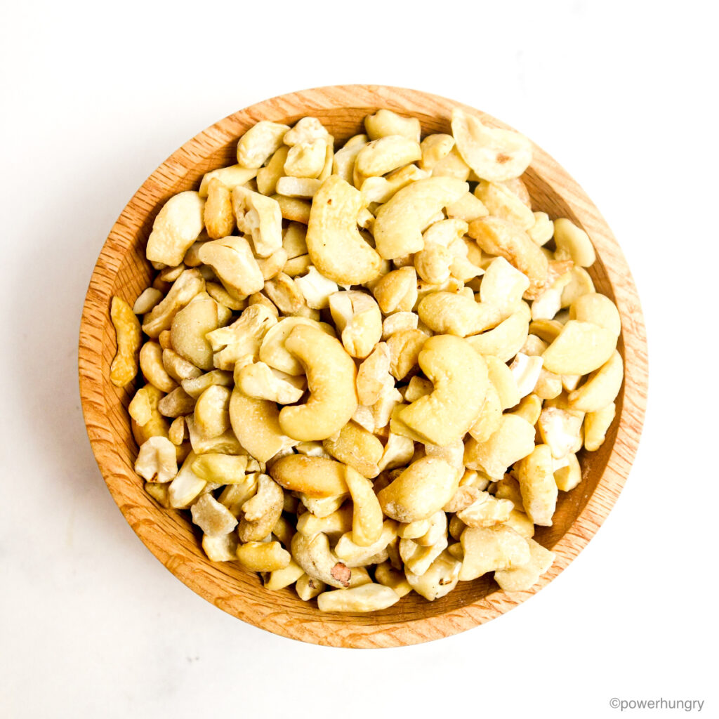 wooden bowl filled with raw cashew pieces