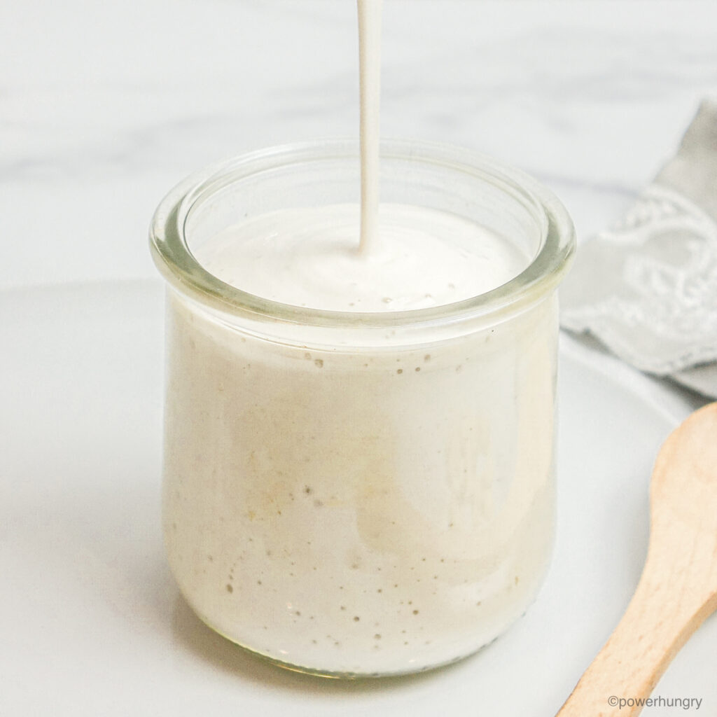 glass jar getting filled with a stream of cashew cream