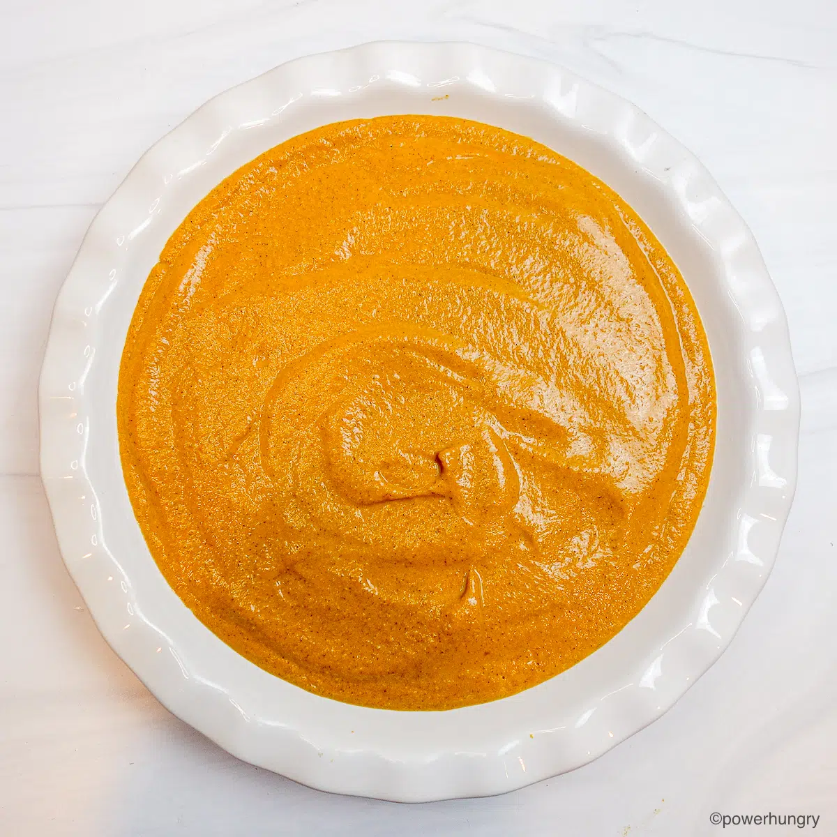 pumpkin pie mixture in white pie dish