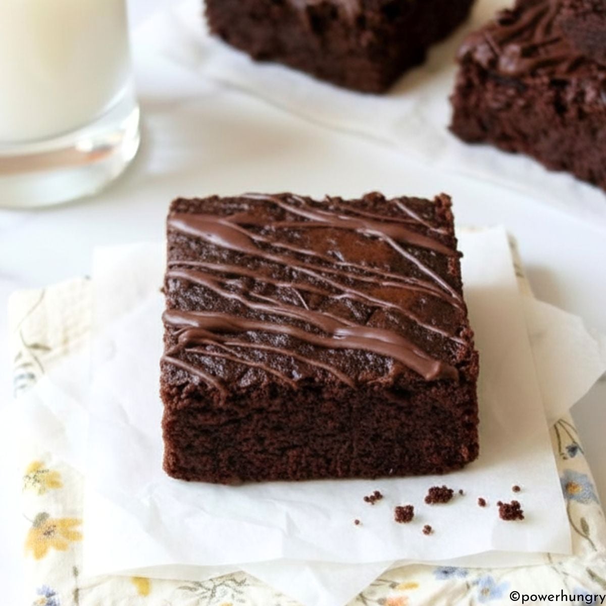 vegan carob almond flour brownie on a napkin with a glass of milk